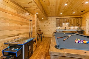 Ein Holzinterieur mit Pooltisch, Stehtischen und Billardkugeln.