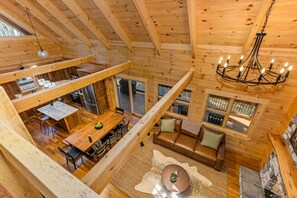 Eine Holzhütte mit Essbereich, einem Wohnzimmer mit Kamin und einem Schlafzimmer im oberen Bereich.