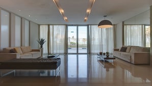Uma sala de estar ampla com um sofá grande, uma mesa de centro e um vaso de planta.