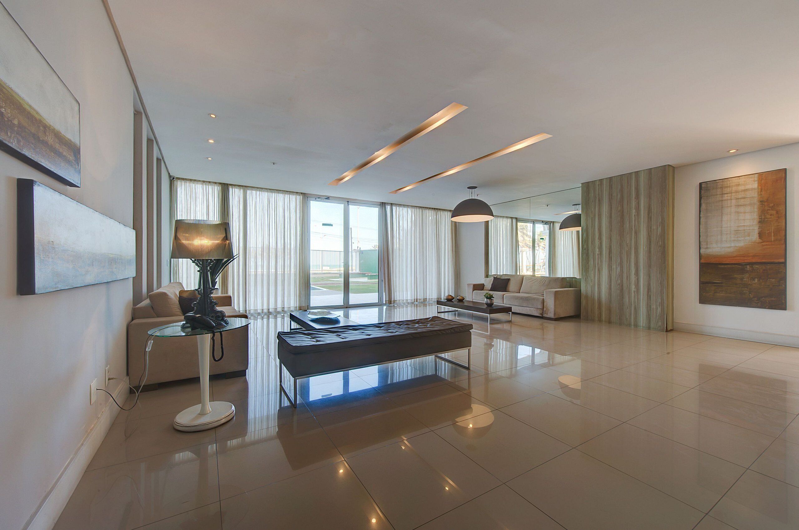 A spacious living room with a modern design, featuring a glass coffee table, a sofa, and a lamp.
