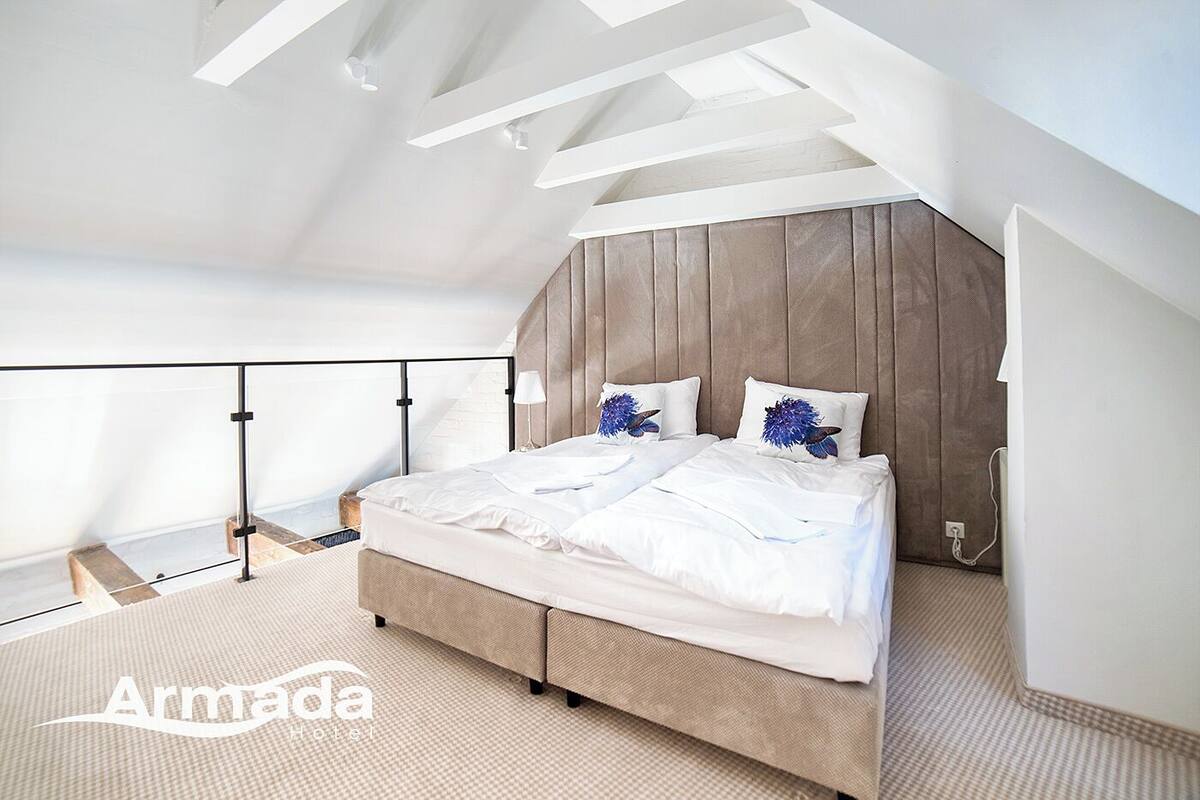 Un dormitorio moderno con una cama grande, cabecera de madera y un balcón con barandilla de cristal.