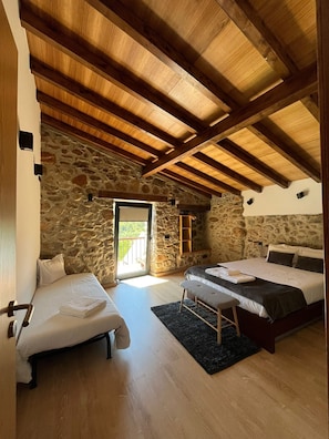 A bedroom with two beds, a stone wall, and a wooden ceiling. - Quinta dos Picarotos (Góis)