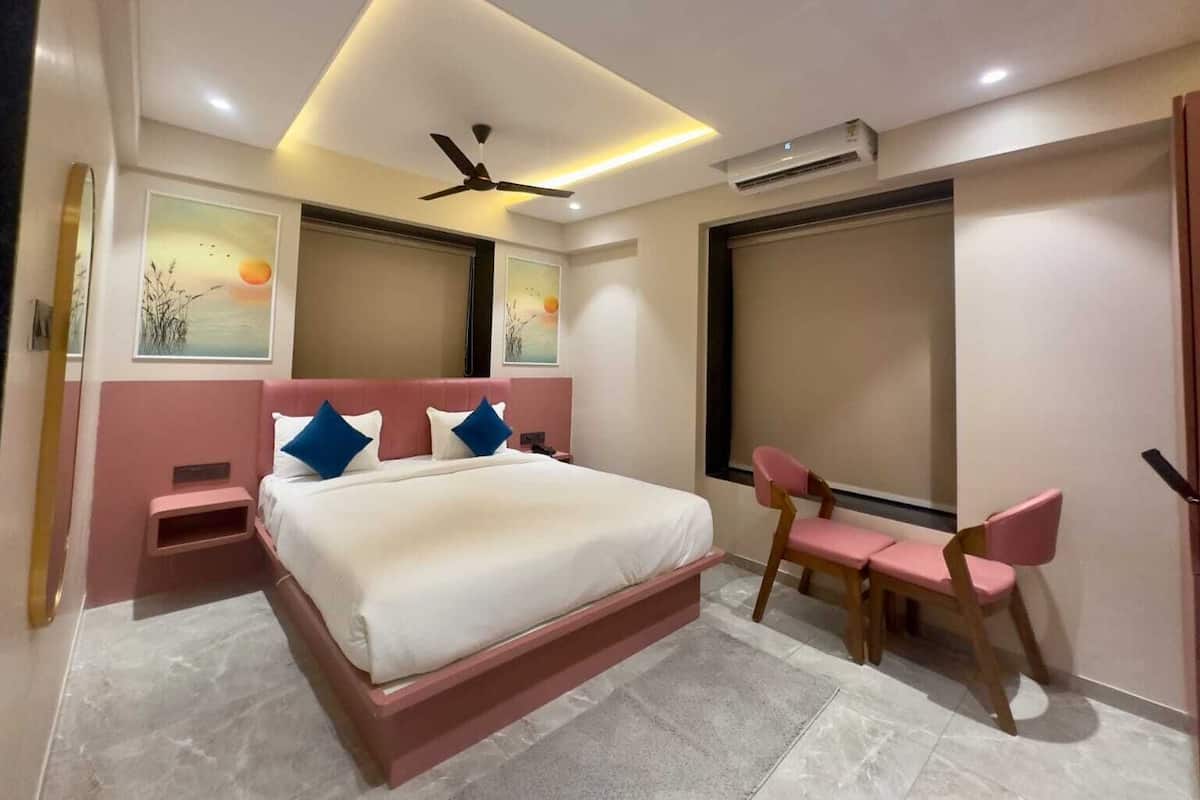 Un dormitorio con cama, escritorio, silla, ventilador de techo y aire acondicionado.