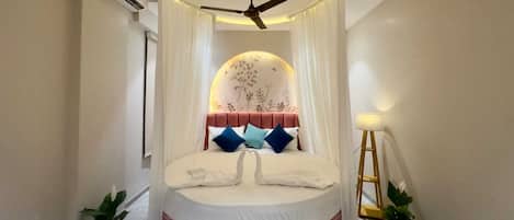 A circular bed with a canopy, a ceiling fan, and two potted plants.