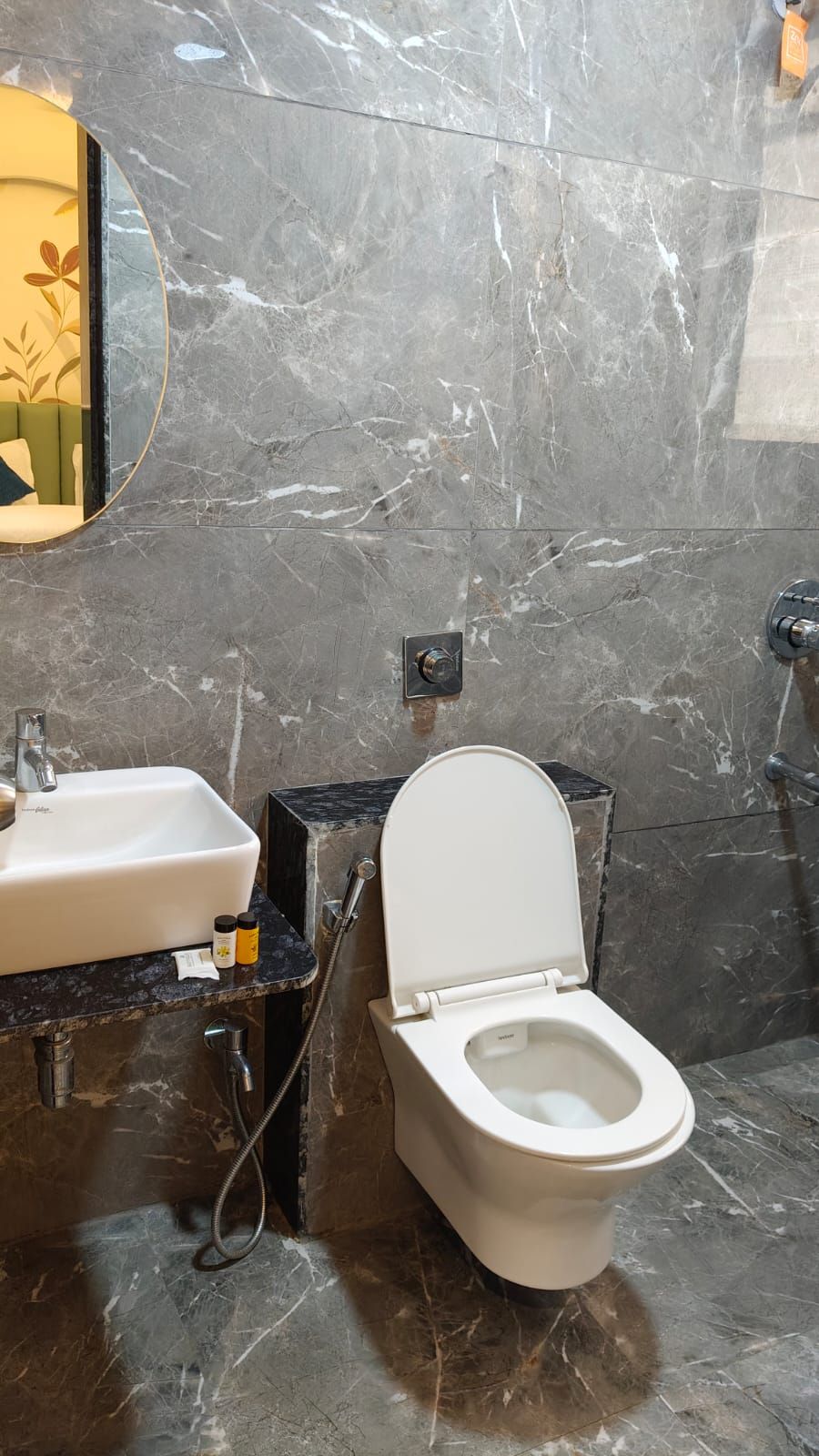 A bathroom with a marble sink, a toilet, and a mirror.