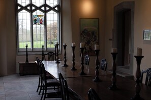 A dining room with a long table, chairs, candle holders, and a stained glass window. - Gatekeepers Cottage (Llandovery)