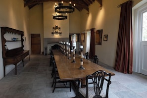 A long dining table with chairs, a chandelier, and a fireplace. - Gatekeepers Cottage (Llandovery)