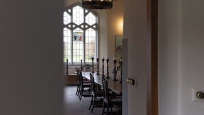 Ein Esszimmer mit einem langen Tisch, Stühlen und Kerzenständern.