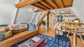 Un espace de vie de style loft avec un plafond en bois, un canapé, une table à manger et un coin cuisine.
