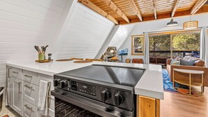 Une cuisine moderne dotée d’une grande cuisinière, de meubles blancs et d’un plafond en bois.
