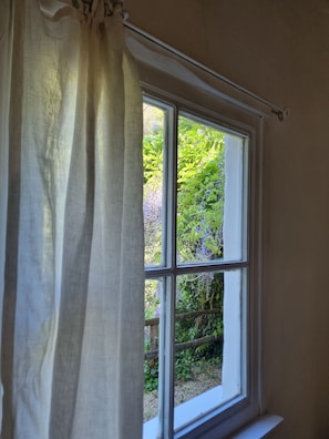 Ein Fenster mit weißem Rahmen und Blick ins Grüne.