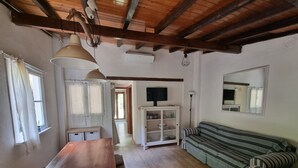 A cozy living room with a wooden table, striped sofa, and a cabinet with glass doors. - Bikers cottage in the woods 5 minutes from the sea, (Finale Ligure)