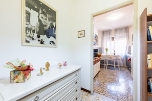 Ein Zimmer mit einem weißen Kommode, einem gerahmten Foto an der Wand, einem kleinen Tisch mit Stühlen und einem Bücherregal.