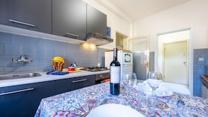 Une cuisine avec des meubles de couleur sombre, une cuisinière à gaz, un évier et un coin repas avec une table mise pour deux personnes.