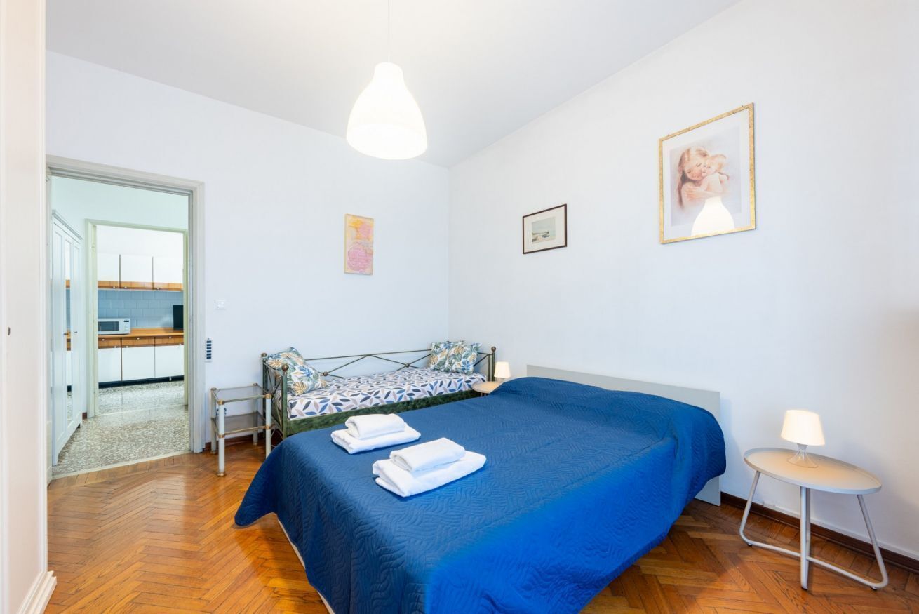 Une chambre à coucher comprenant un lit, une table de chevet, une lampe et une porte donnant sur une salle de bain.