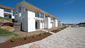 A modern building with a flat roof, large windows, and a paved driveway. - Havna Tjøme Apartments  (Faerder)