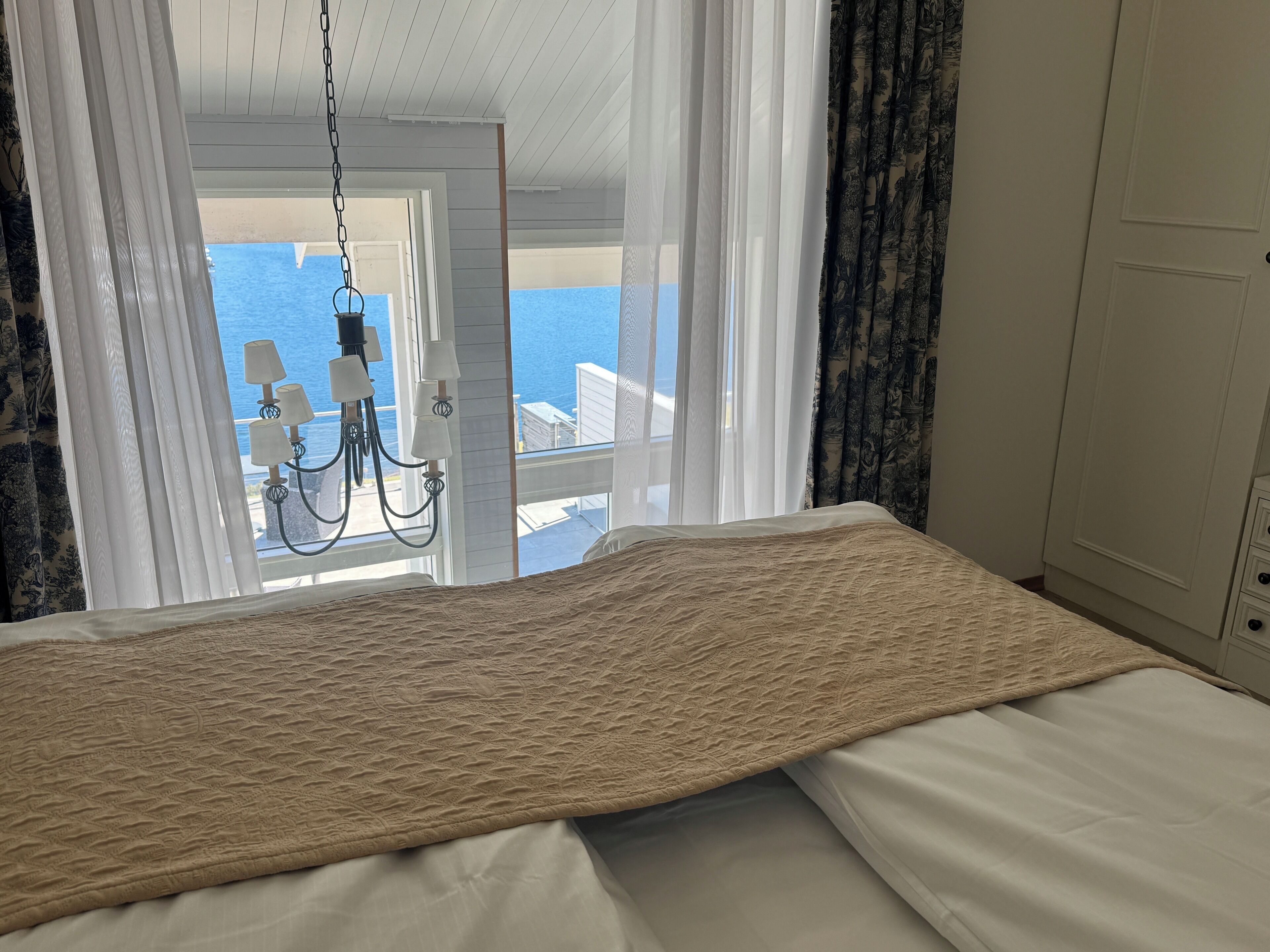 Une chambre à coucher avec un lit, un lustre et une vue sur la mer.