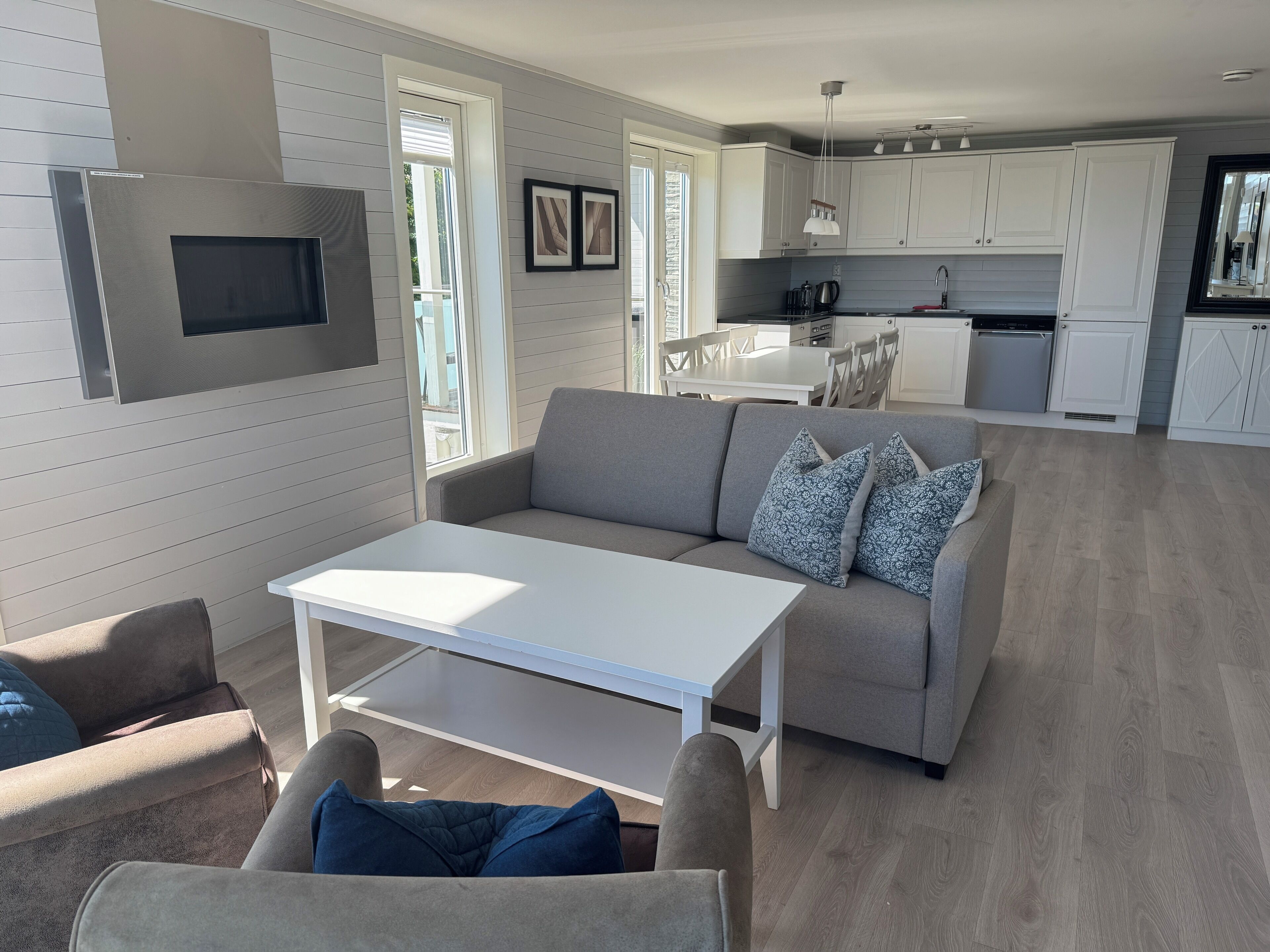 A modern living room with a sofa, a coffee table, and a dining area with a table and chairs.