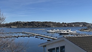 A marina with boats docked, a clear sky, and a hilly landscape in the background. - Havna Tjøme Apartments  (Faerder)