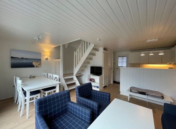 A compact living space with a dining area, sofa, staircase, and kitchenette. - Havna Tjøme Apartments  (Faerder)