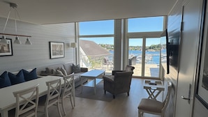 A modern interior with a dining area, seating, and a view of the marina. - Havna Tjøme Apartments  (Faerder)