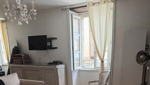 Una sala de estar con un sofá, una mesa de centro, un televisor y una ventana con cortinas.