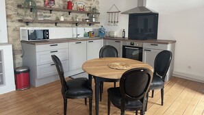Una cocina moderna con armarios blancos, una mesa de comedor de madera y sillas negras.