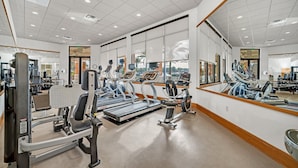 Een sportschool met loopbanden, gewichtapparaten en spiegels.