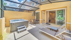 Een buitenterras met een jacuzzi, lounge stoelen en een overdekte zithoek.