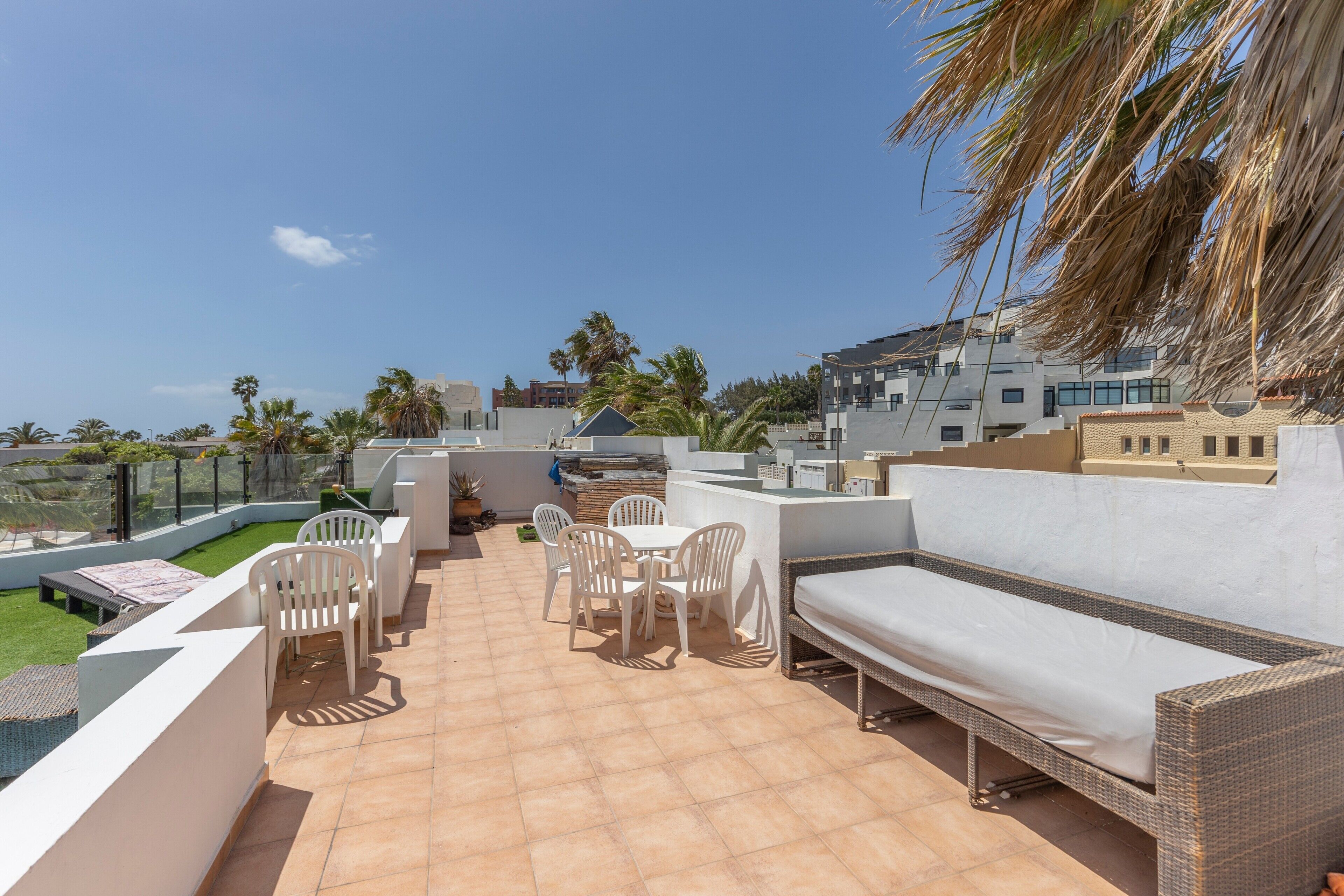 A rooftop terrace with outdoor furniture, a barbecue area, and a view of the surrounding buildings.