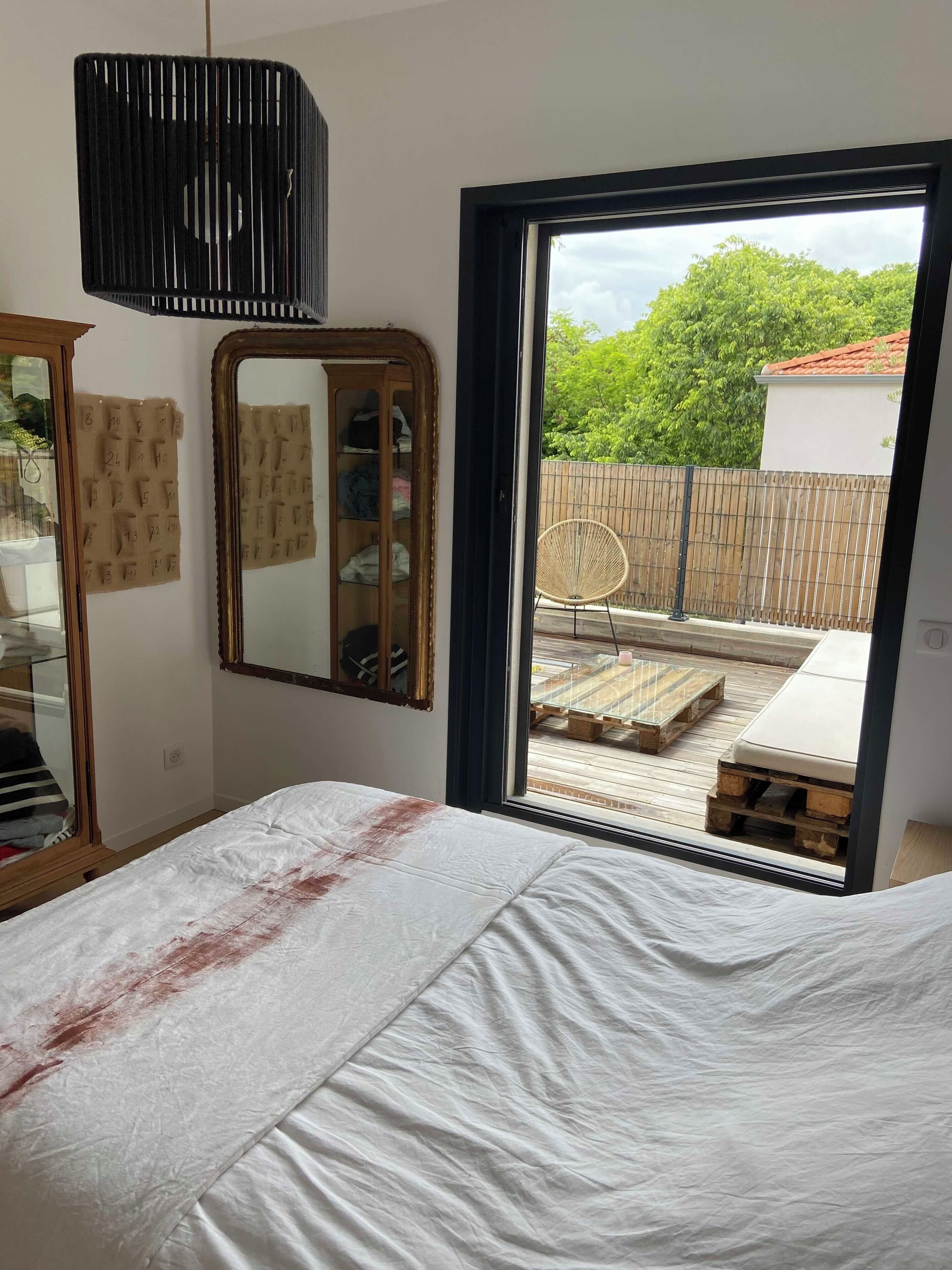 Ein Schlafzimmer mit Bett, Spiegel, Kleiderschrank und Blick auf den Balkon.