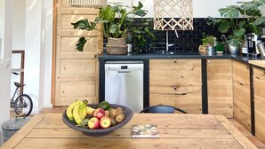 Eine moderne Küche mit Holztisch, Obstschale und verschiedenen Pflanzen.