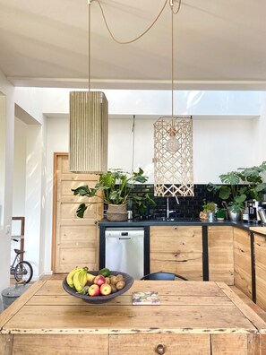 Eine moderne Küche mit Holztisch, Obstschale und verschiedenen Pflanzen.
