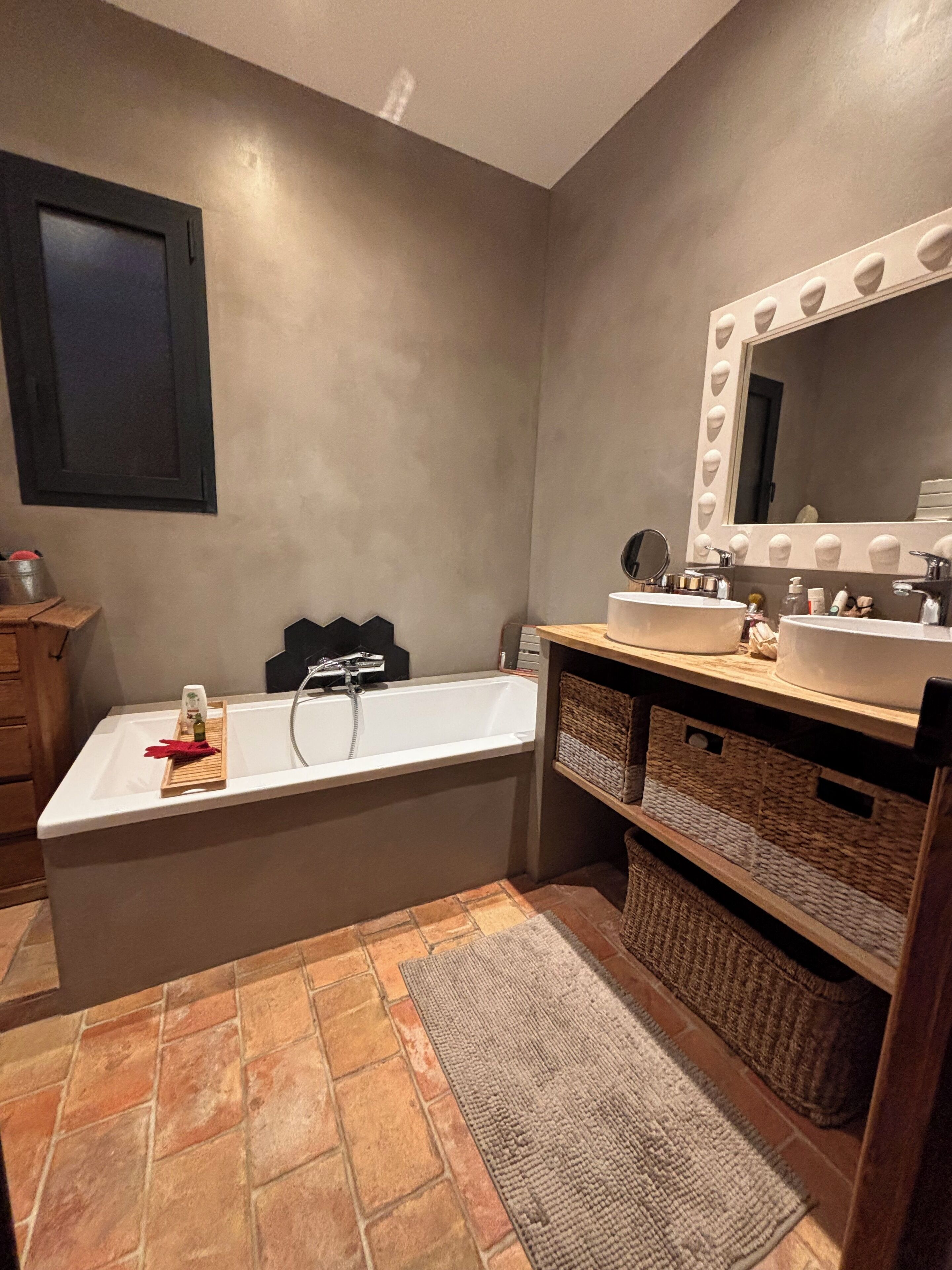 Une salle de bain moderne avec une baignoire sur pieds, un meuble-lavabo avec un miroir et un sol carrelé.
