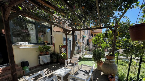 An outdoor patio with white plastic chairs and tables, surrounded by potted plants and a pergola with hanging plants. - Casa Irene by the beach with garden and A/C (Monterosso al Mare)