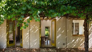 Un bâtiment doté de plusieurs entrées menant à des espaces intérieurs, entouré d’un arbre aux feuilles vertes.