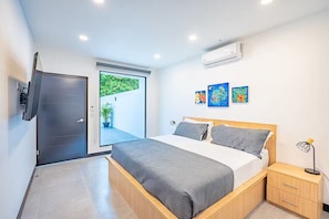 Ein modernes Schlafzimmer mit einem Bett, Nachttischen, einer Klimaanlage und Kunstwerken an der Wand.