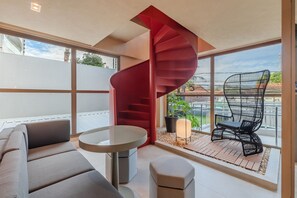 A modern interior with a spiral staircase, a sofa, a round table, and a balcony with a chair and plants. - Jsmart Guararapes #502 - Modern apt by Carpediem (Fortaleza)