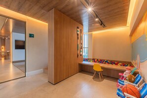 Ein Kinderspielbereich mit Ballgrube, Sitzgelegenheiten und Spielzeug.