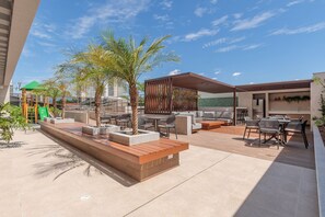 An outdoor patio area with seating, palm trees, and a play structure.