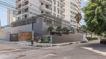 Un edificio moderno con balcón, entrada protegida y vista a la calle.