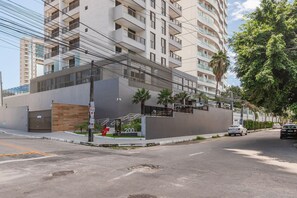 A modern building with a balcony, a gated entrance, and a street view.