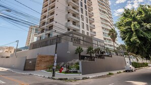 Un edificio moderno de gran altura con varios balcones y una entrada protegida por un portón.