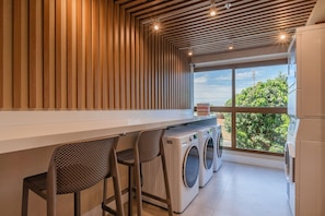 A modern laundry room with a large window, a washing machine, and two bar stools. - Jsmart Guararapes #502 - Modern apt by Carpediem (Fortaleza)