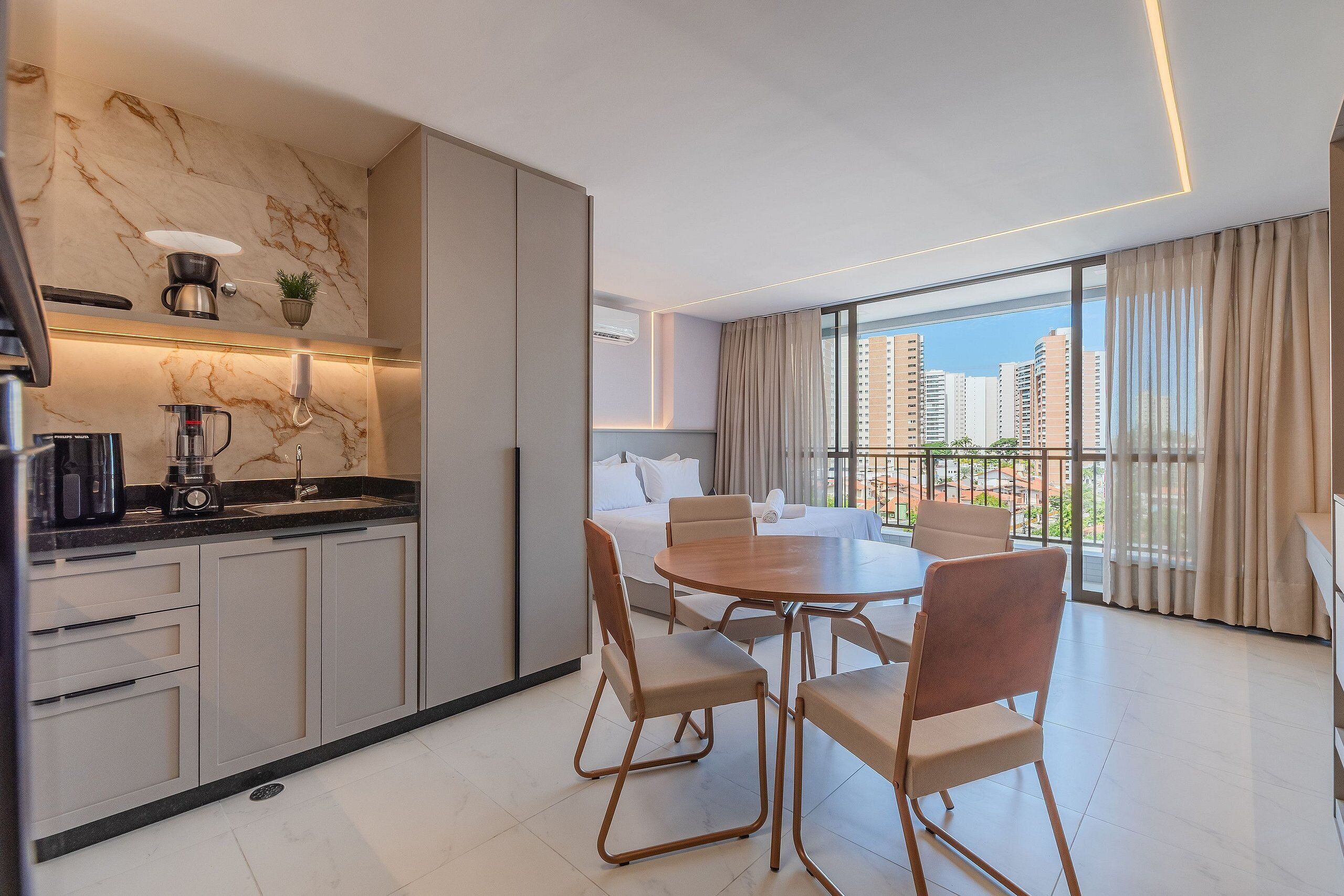 Una cocina moderna con salpicadero de mármol, un comedor con mesa y sillas redondas, y un balcón con vistas a la ciudad.