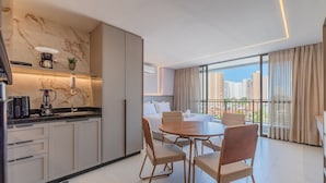 Eine moderne Küche mit Marmorfliesenspiegel, ein Essbereich mit rundem Tisch und Stühlen sowie ein Balkon mit Blick auf die Stadt.