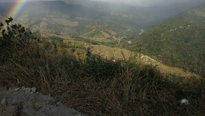 A mountainous landscape with a visible rainbow and a valley below. - Peaceful campground in Monteverde perfect for nature lovers (San Luis de Monteverde)