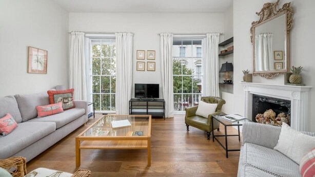 A living room with a sofa, a coffee table, a television, and a fireplace. - Spacious flat near Victoria and Warwick Square (London)