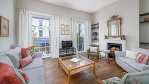A living room with a sofa, armchair, coffee table, fireplace, and large windows. - Spacious flat near Victoria and Warwick Square (London)