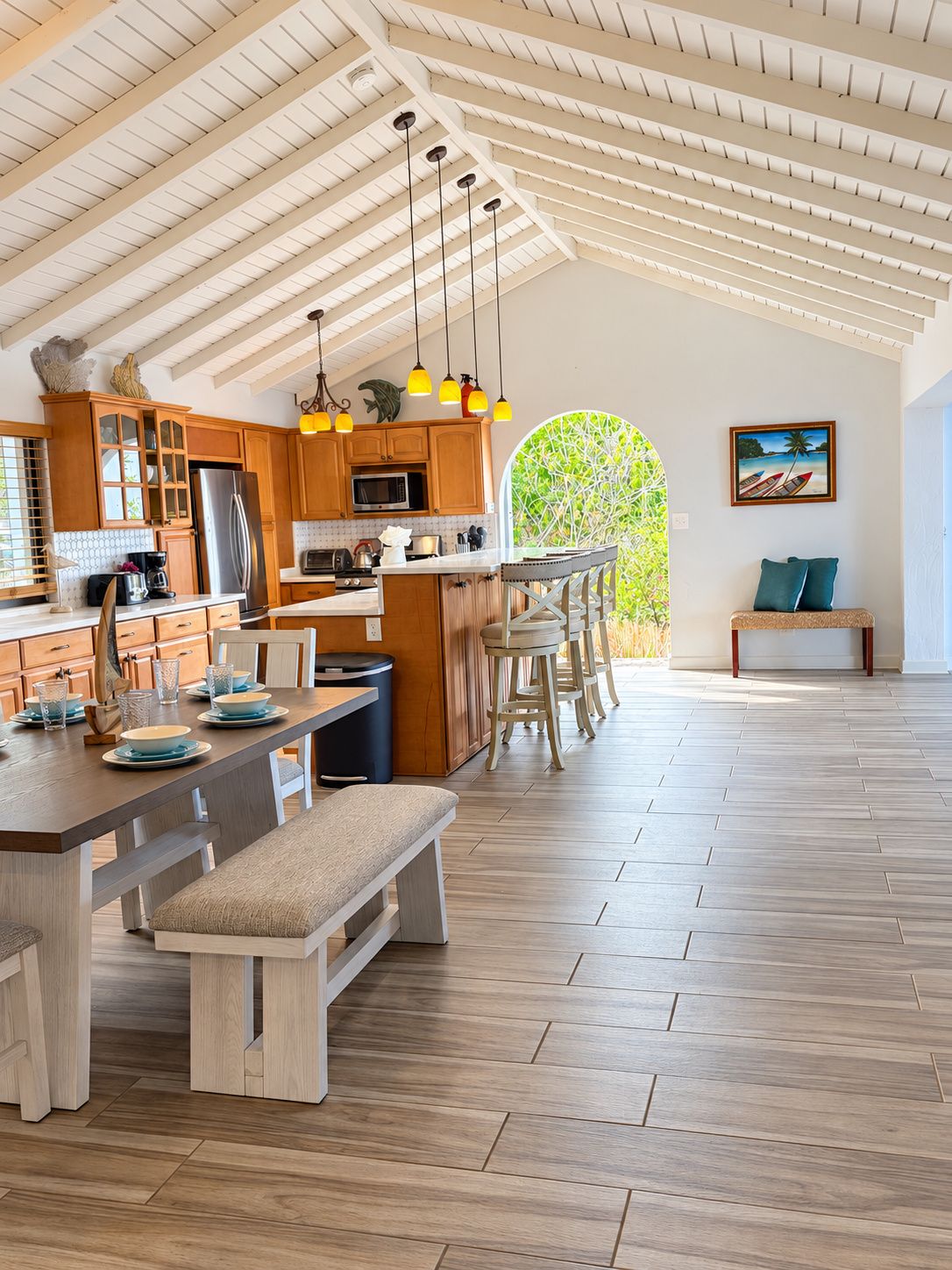 A spacious kitchen with wooden cabinets, a central island, and pendant lighting.